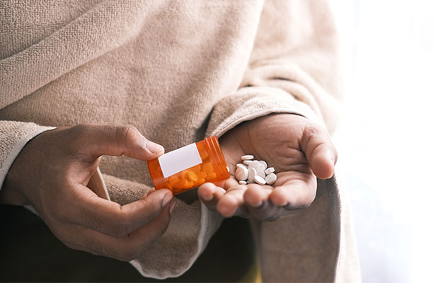 photo showing hand holding drug tablet