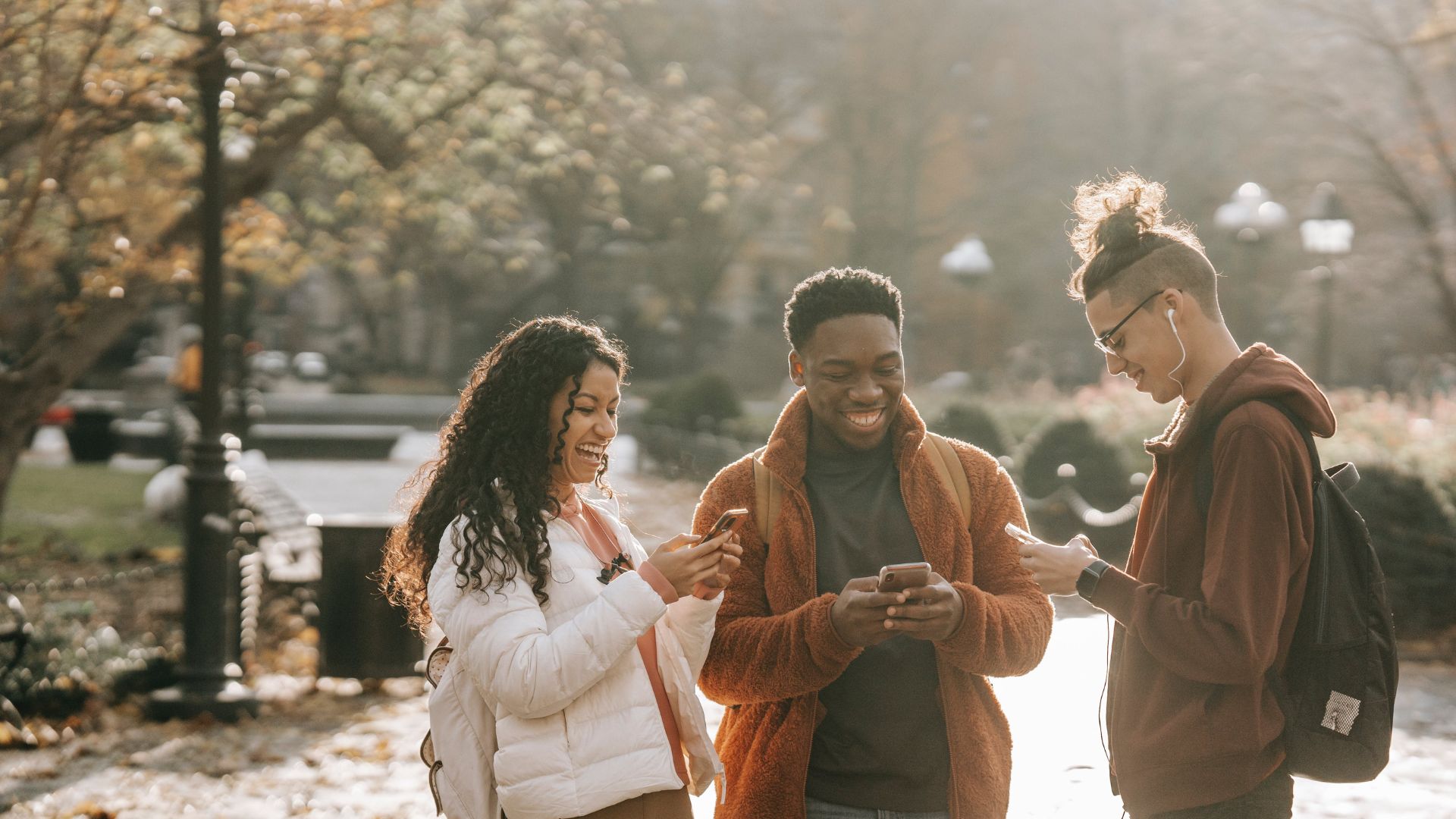 photo of young students using smartphones in city park