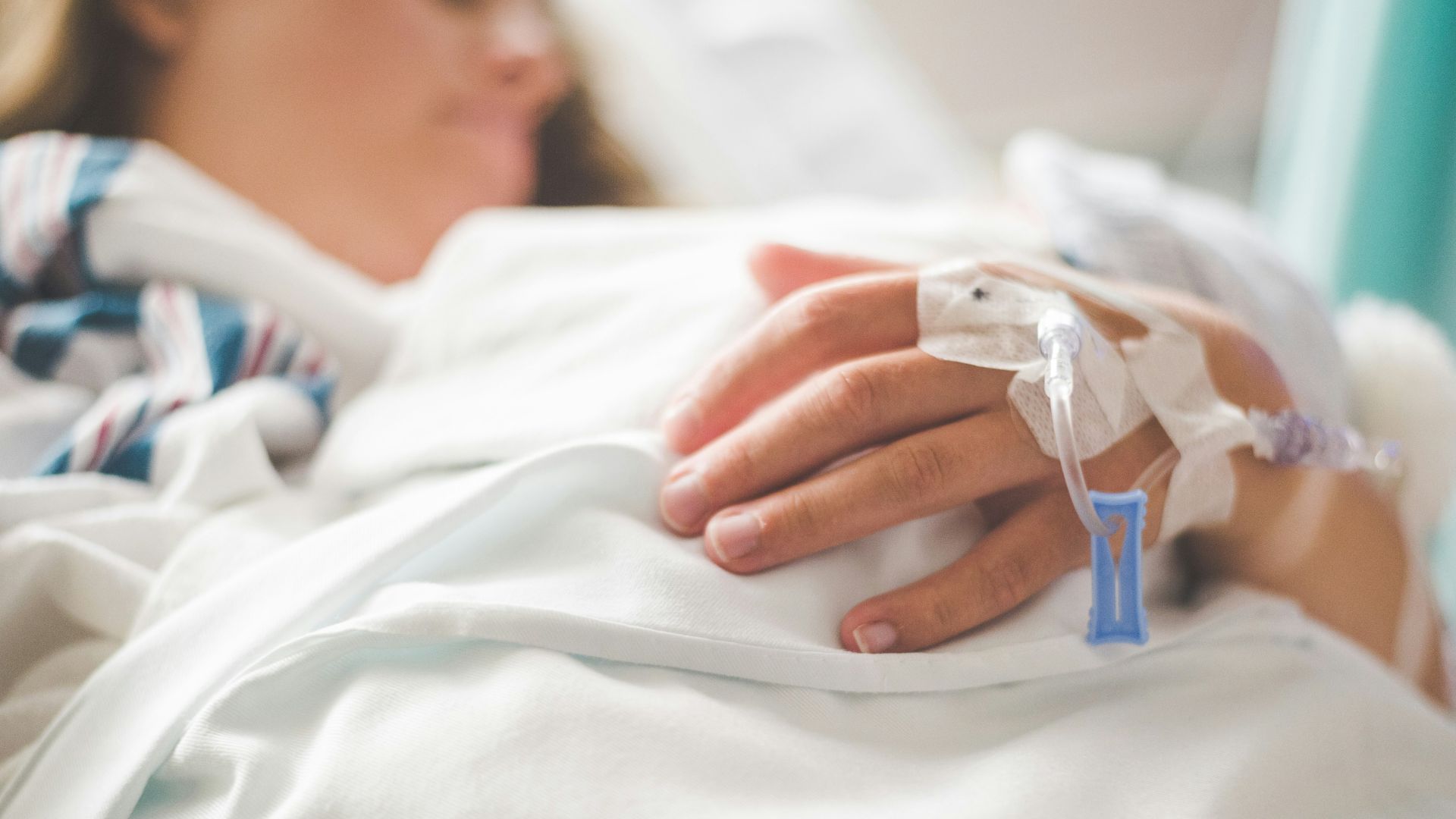 woman laying in a hospital bed with an iv in her hand