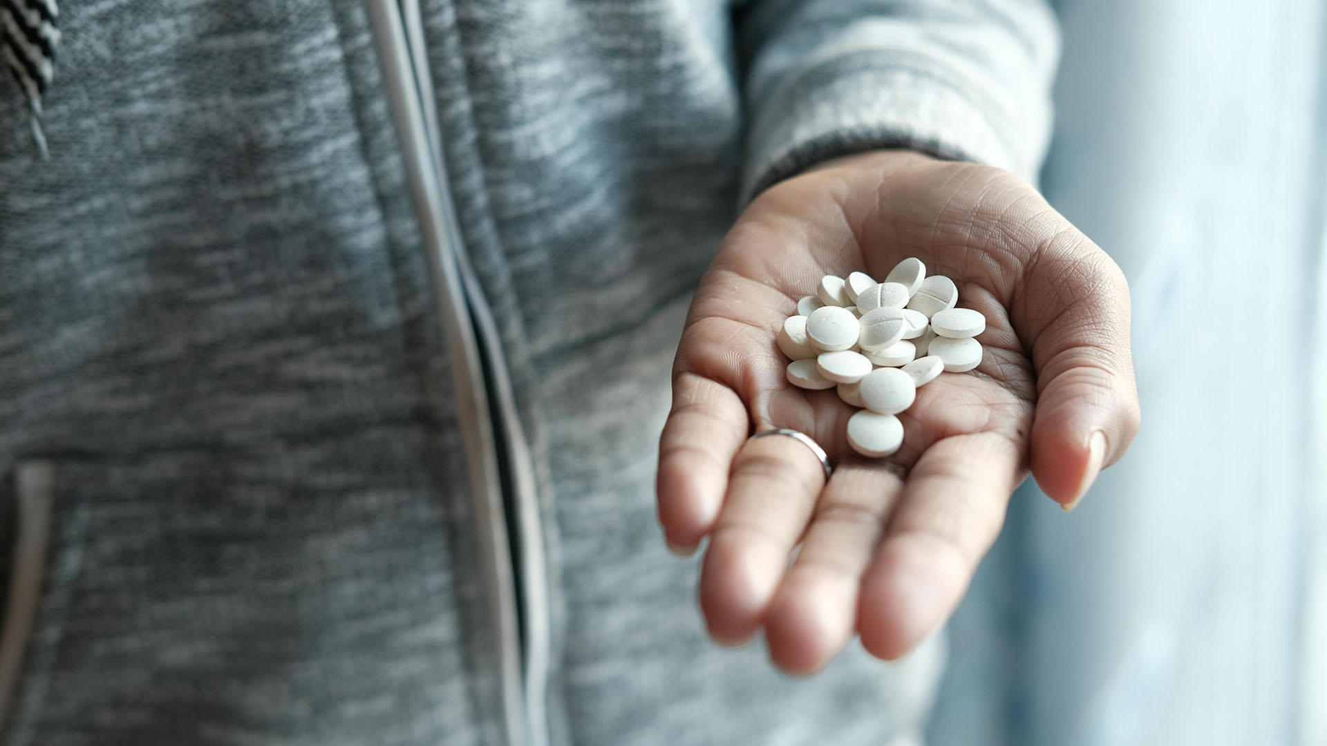 person holding white round medication tablets