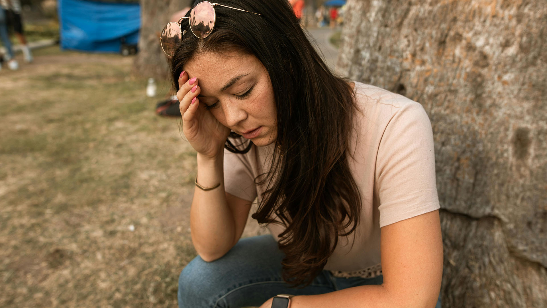 woman with eyes closed touching her forehead