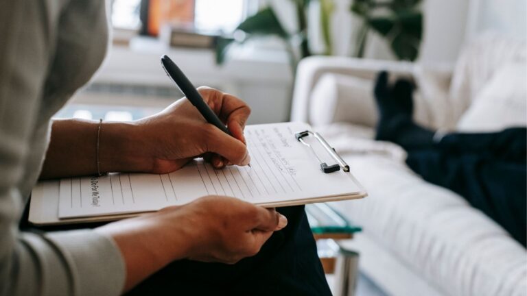 Therapist taking notes on clipboard during a session