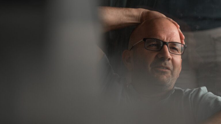 Bald man in glasses relaxing indoors