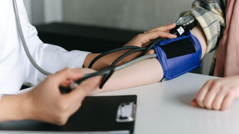 healthcare worker uses a sphygmomanometer to check a patient's blood pressure