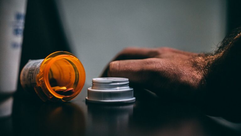 prescription bottle and hand on a table