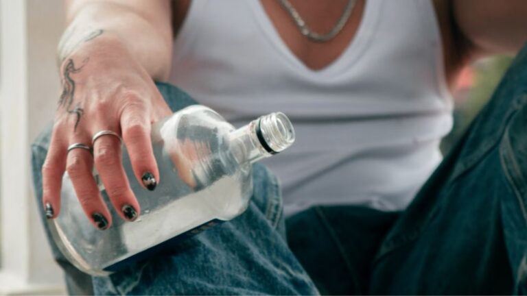 young man with tattoos holding an empty bottle