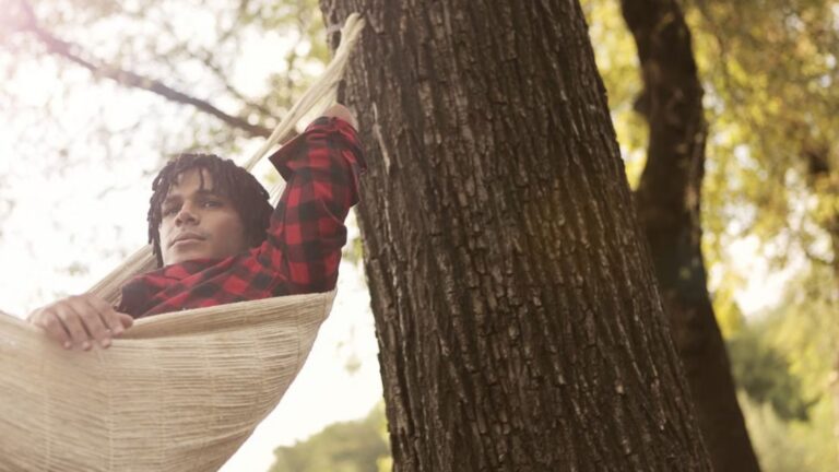 A man in a plaid shirt relaxes in a hammock outdoors