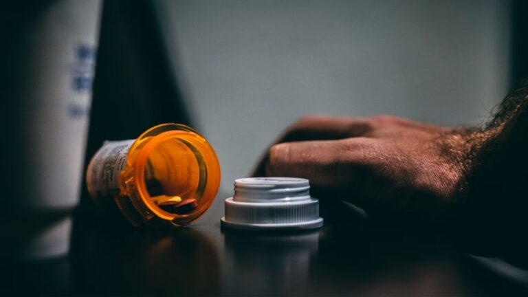 open prescription bottle and hand on a table